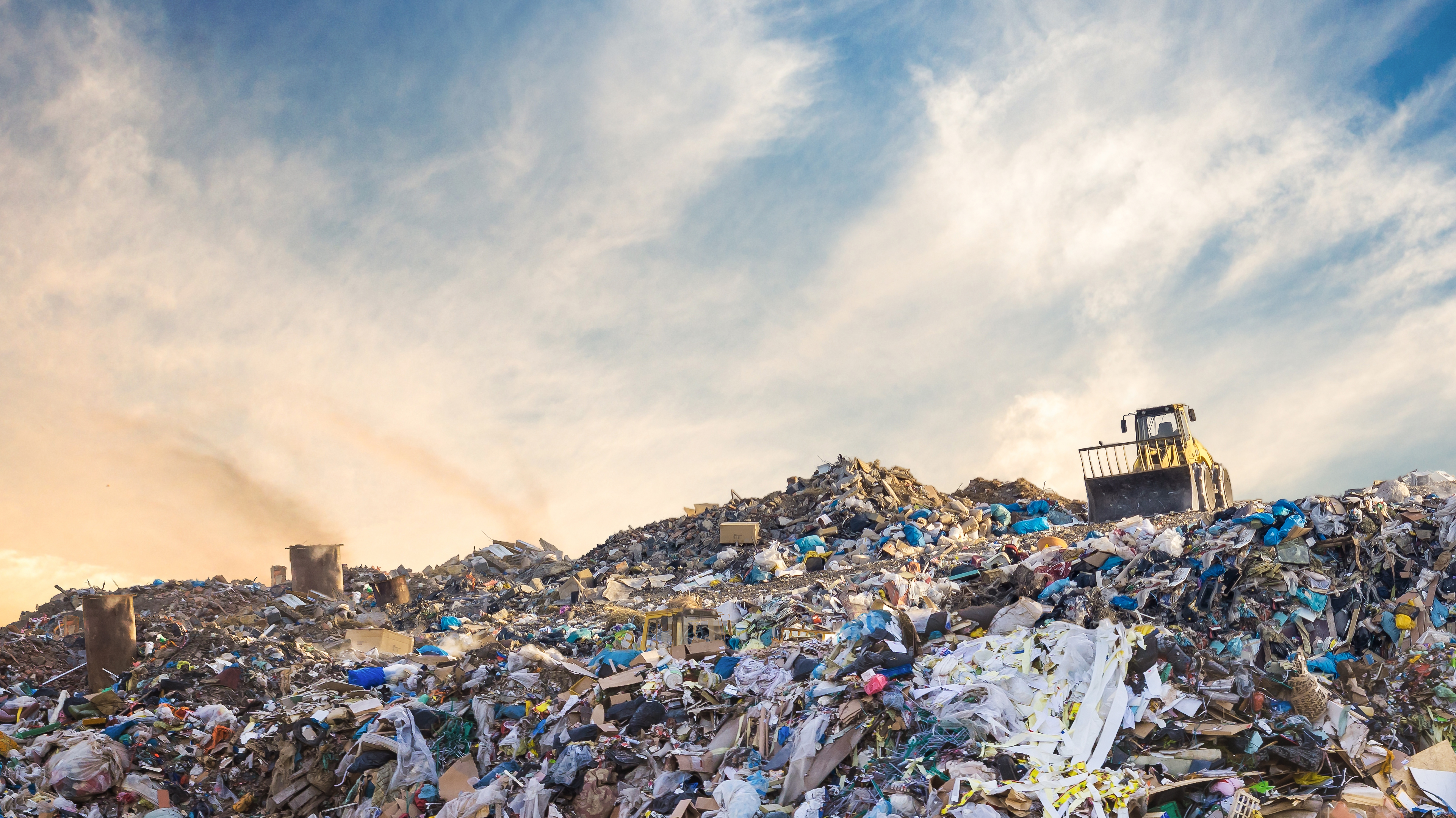 Bulldozer at a landfill site full of plastic
